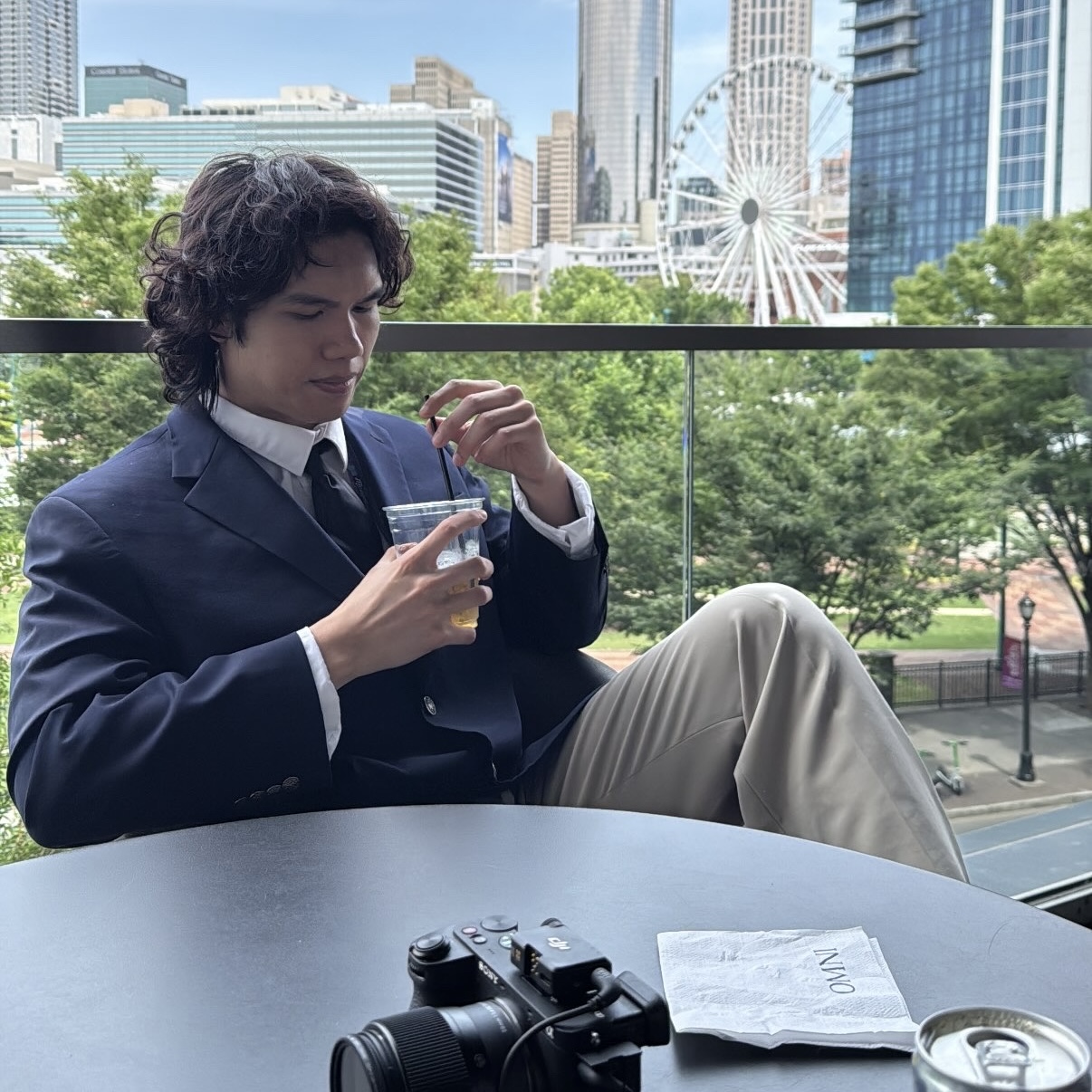 Professional headshot of Tommer in navy suit with city skyline